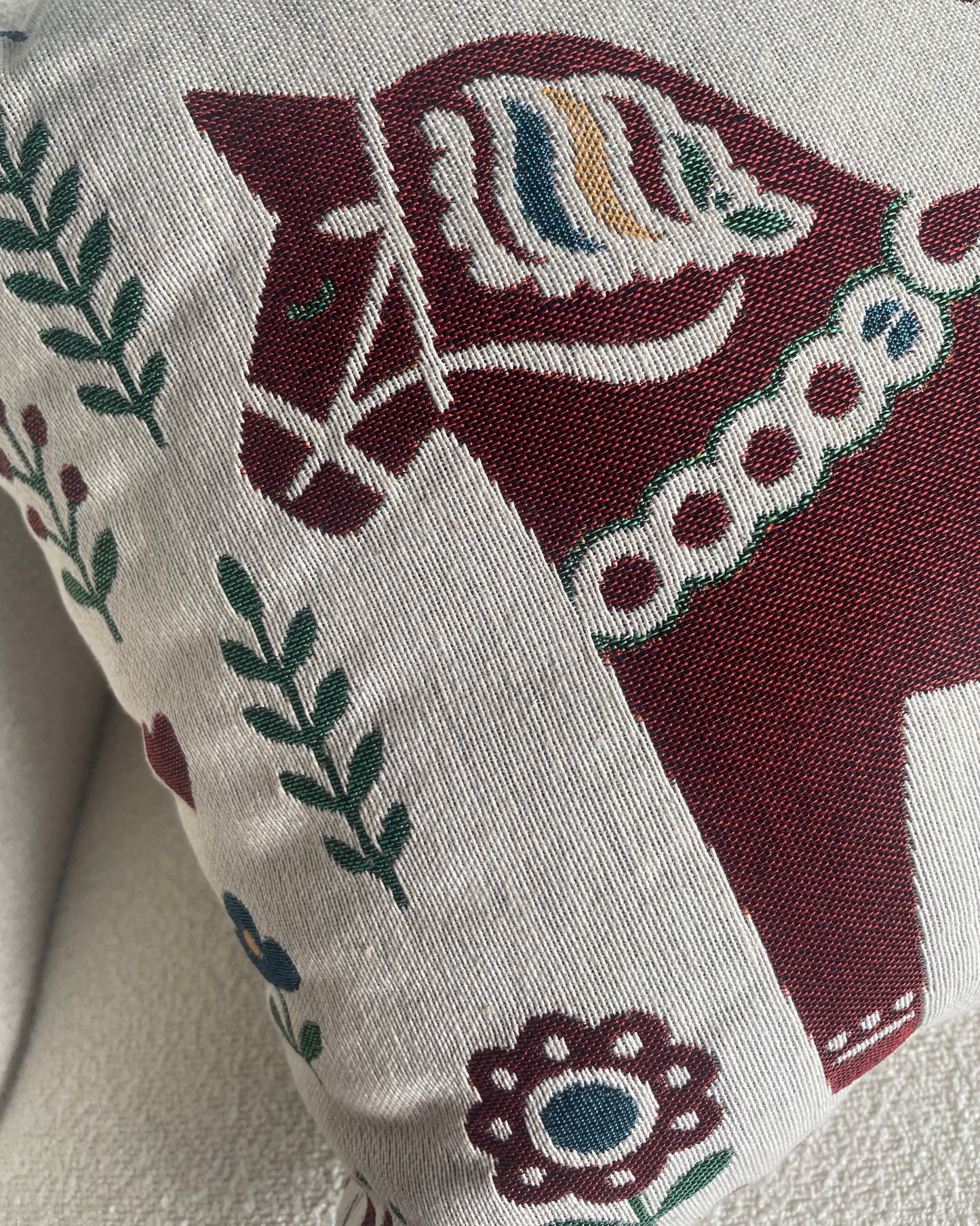 A close-up of a woven throw pillow featuring a traditional Swedish horse design.