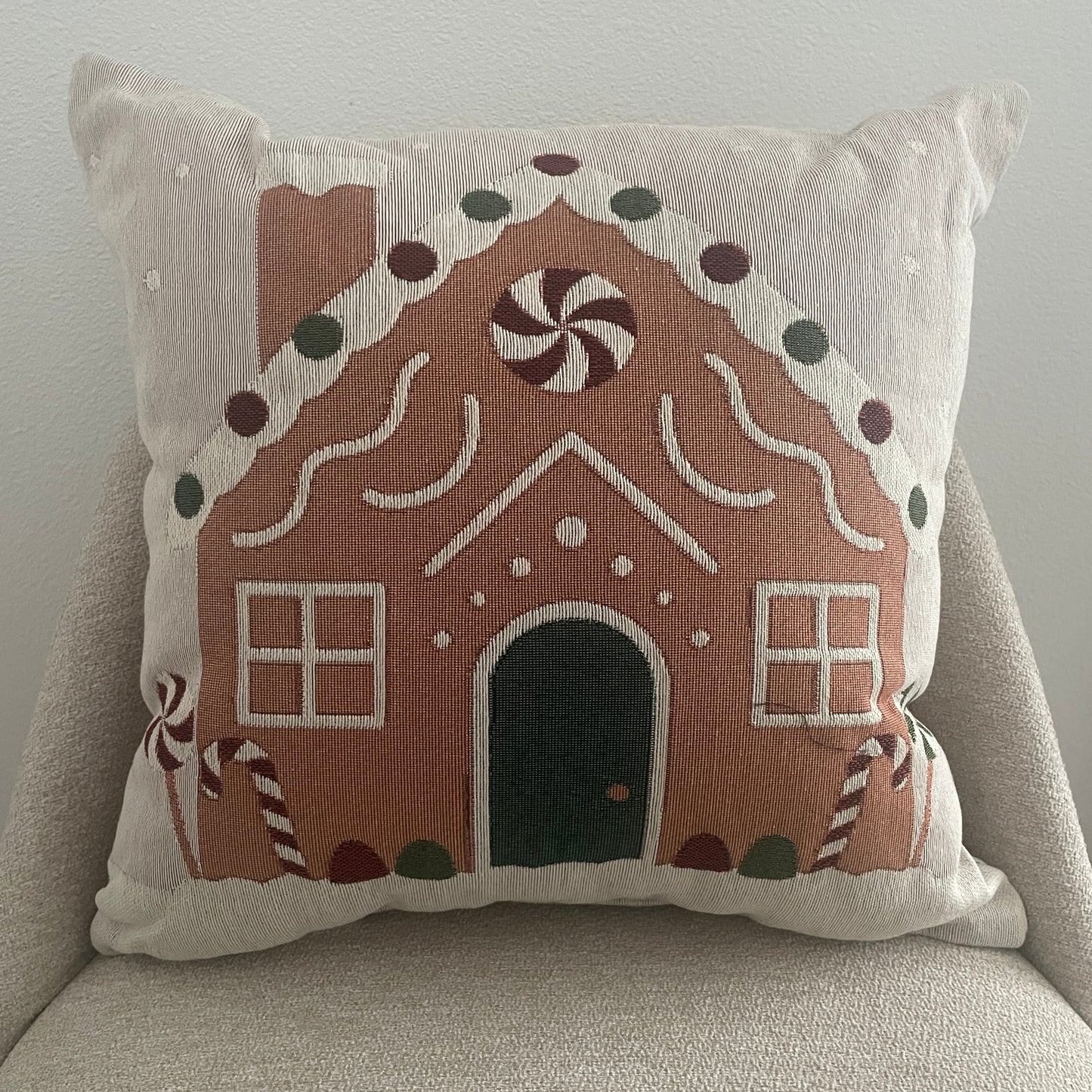 Decorative pillow with gingerbread house design on a neutral background