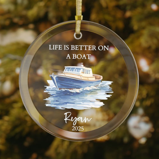 Personalized glass Christmas ornament featuring a blue and tan cabin cruiser boat on the water with the phrase "Life Is Better On A Boat," customized with the name and year.