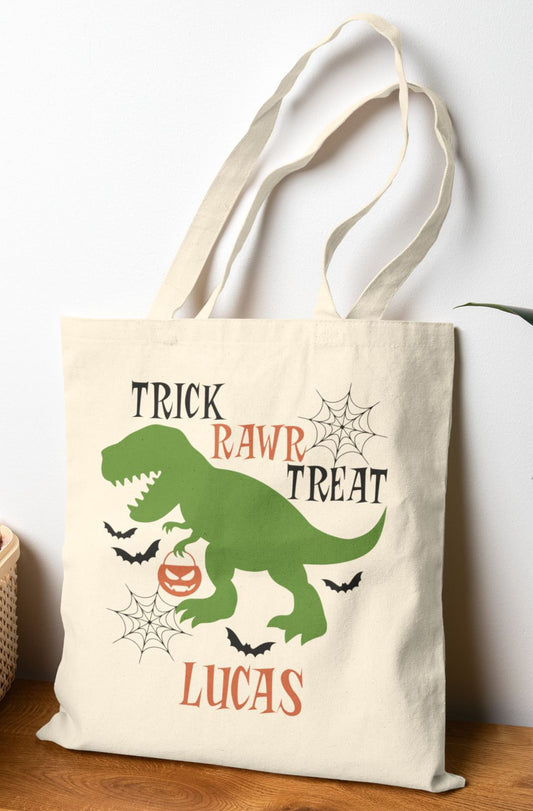 Personalized Halloween dinosaur tote bag for kids – Trick Rawr Treat canvas bag with green T-rex, bats, pumpkin, and custom name for trick-or-treating fun.