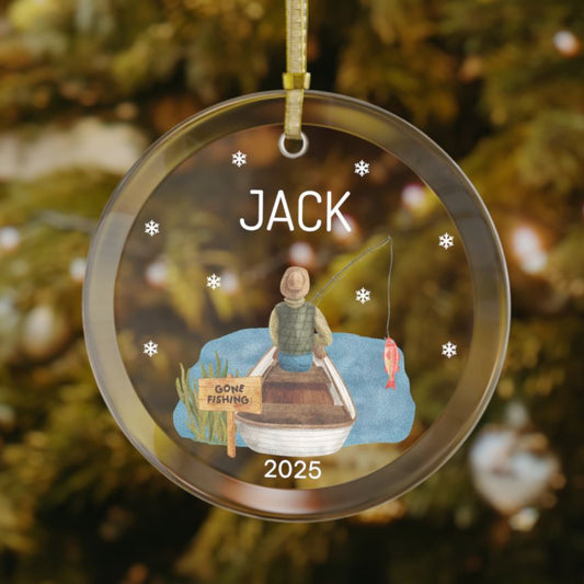 Personalized fishing ornament with a custom name, featuring a man sitting in a boat on the water, a "Gone Fishing" sign, a red fish on the line, snowflakes around the design, and the year at the bottom.