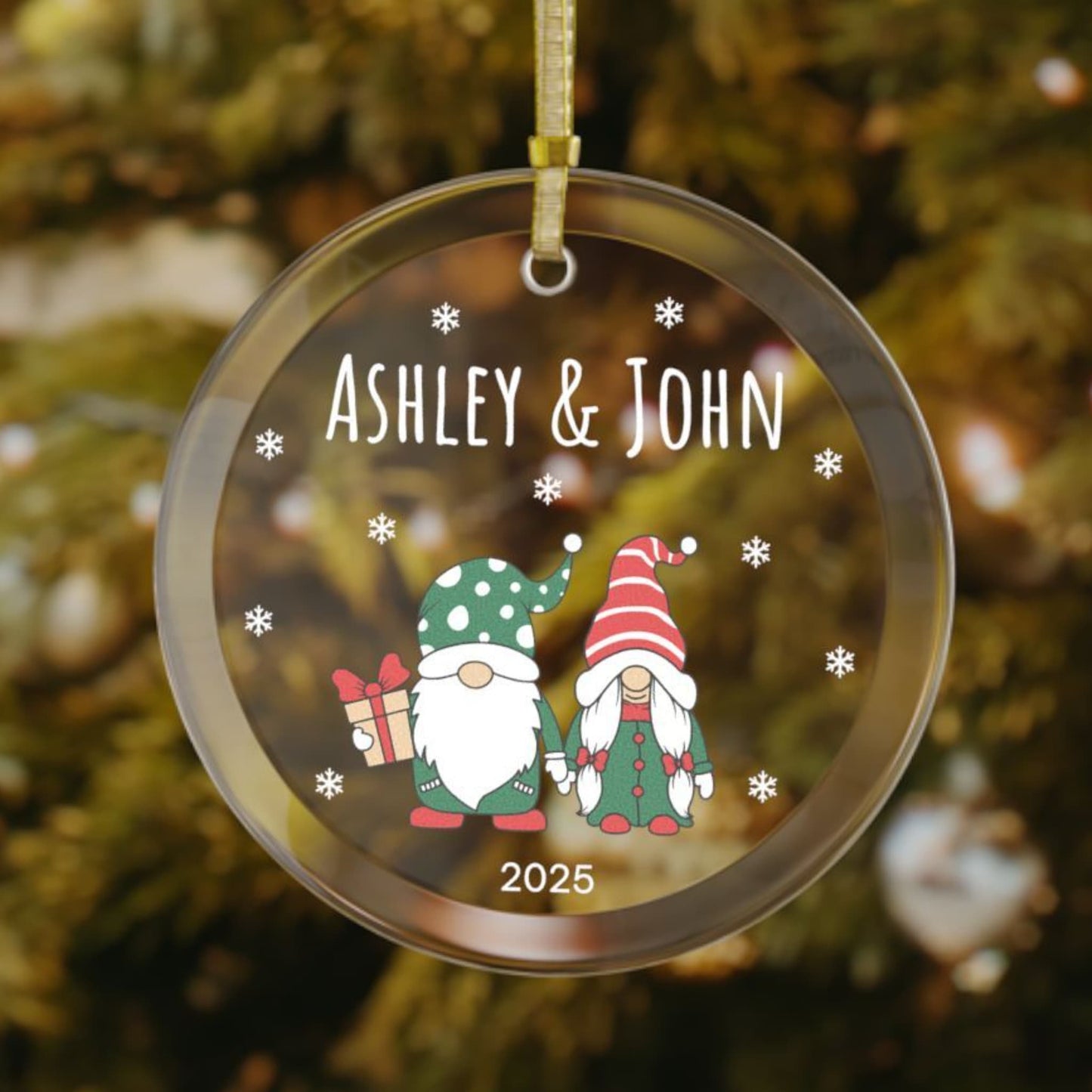 Glass ornament with a festive gnome couple dressed in red and green, personalized with the couple's first names and the year, surrounded by white snowflakes.