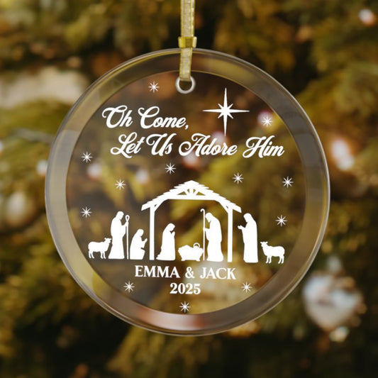 Personalized nativity glass ornament with "Oh Come, Let Us Adore Him" text, Holy Family silhouette, custom couple names "Emma & Jack," and year 2025.