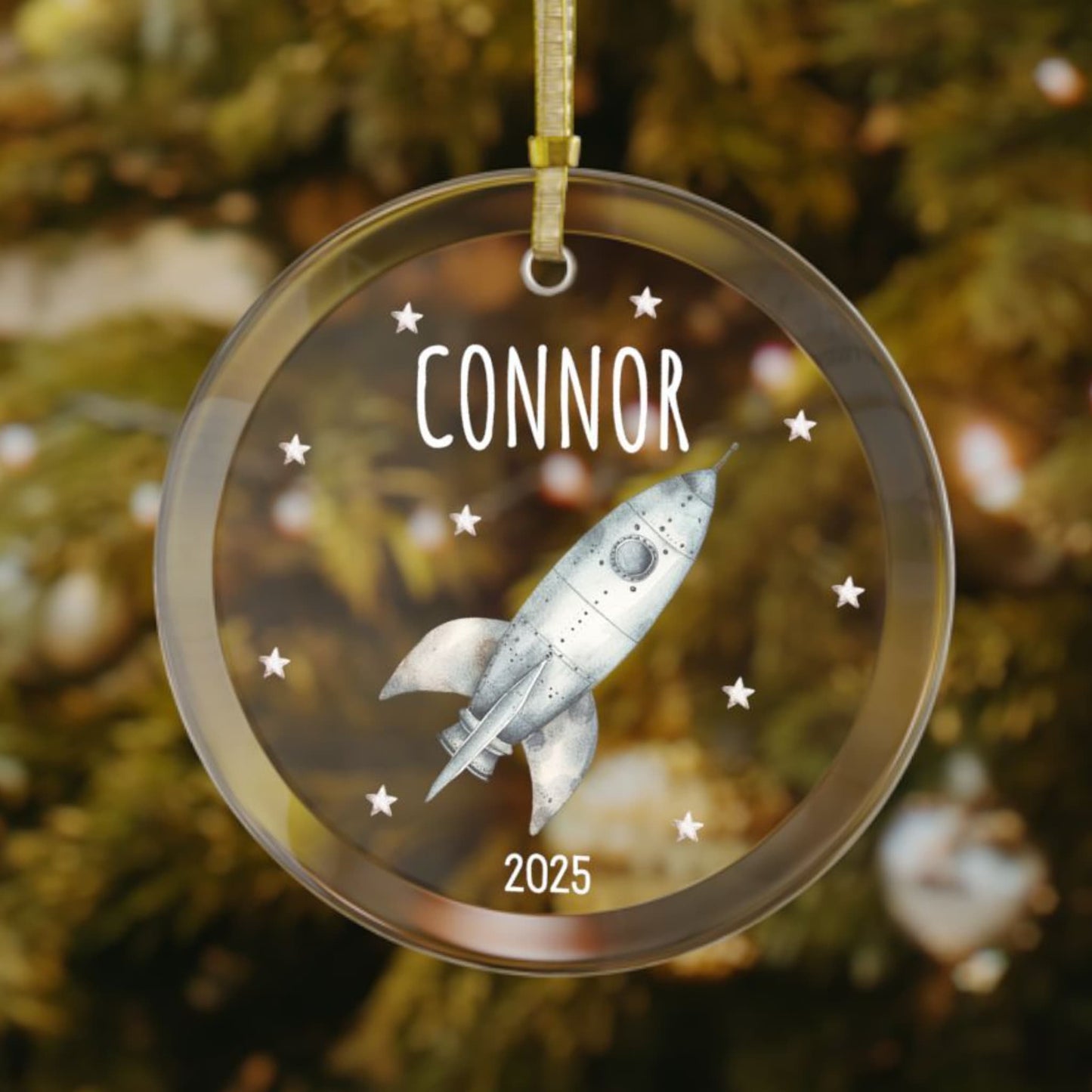 Personalized rocket Christmas glass ornament with custom name and year, featuring a silver rocket ship and stars. A unique holiday gift for space-loving kids and adults.