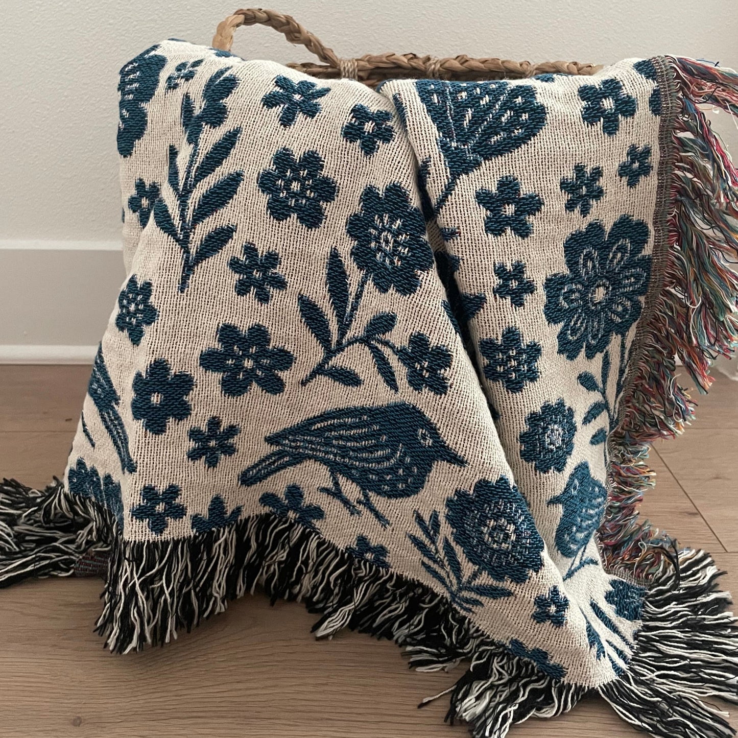 Floral and bird patterned throw blanket with fringed edges.