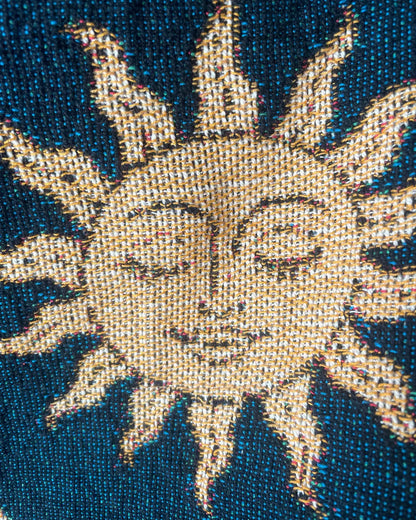 Close-up of a golden sun face on a dark navy celestial woven throw blanket, showing the 100% cotton jacquard weave and intricate woven details.
