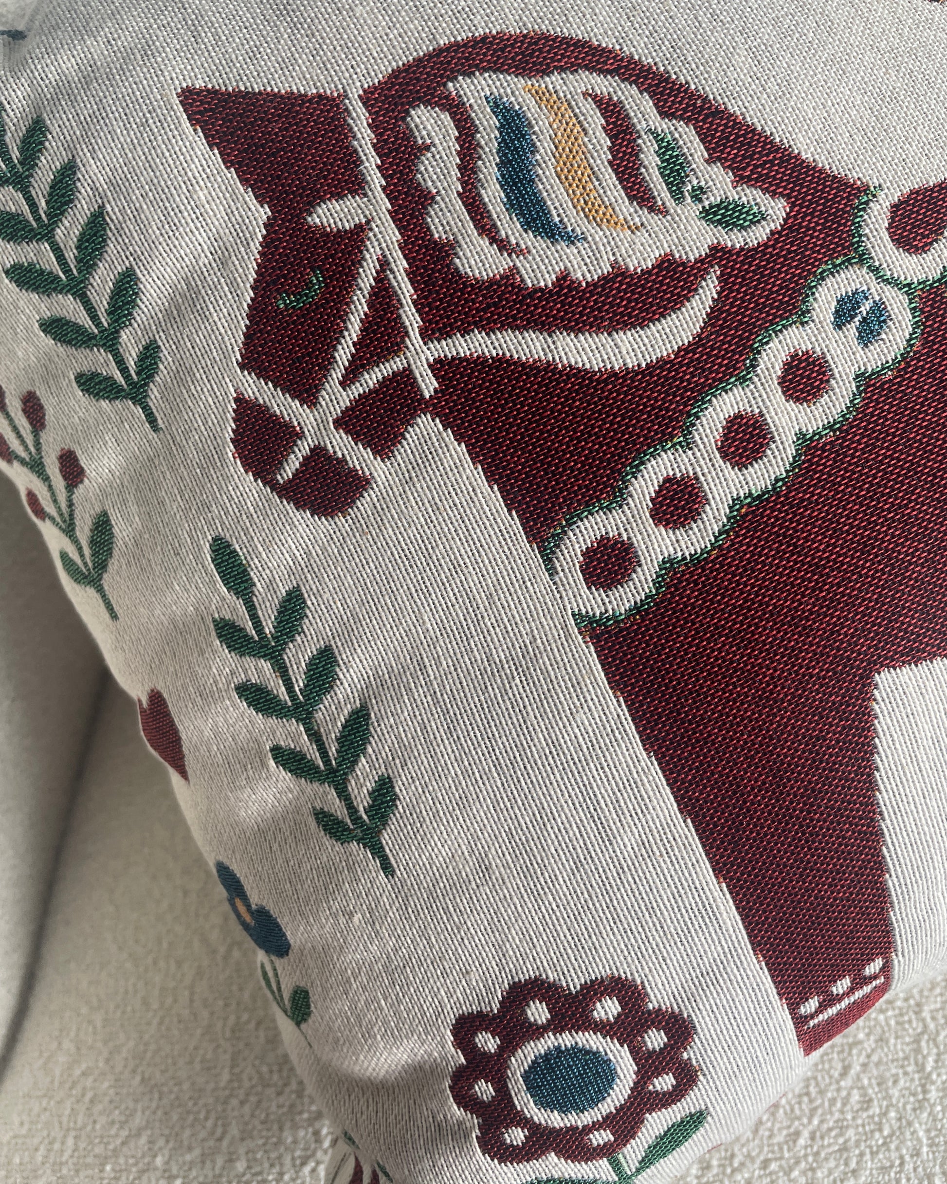A close-up of a woven throw pillow featuring a traditional Swedish horse design.