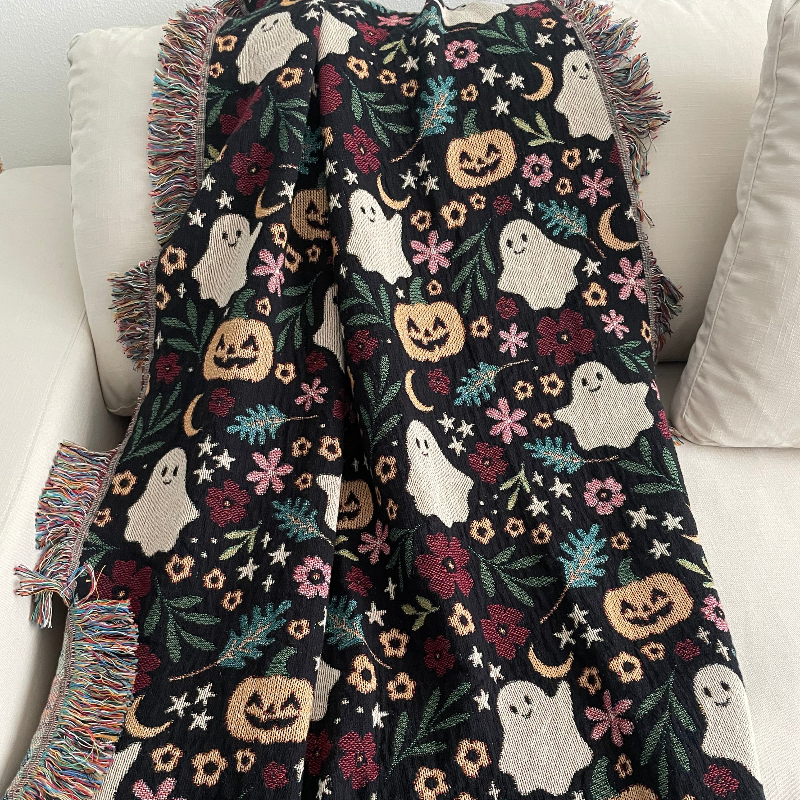 Halloween-themed blanket with ghosts, pumpkins, and crescent moons, and stars draped over a couch.