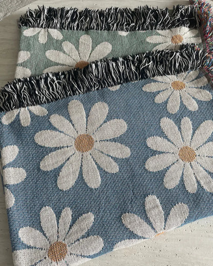 Dusty blue and sage green daisy woven throw blankets with black-and-white and colorful fringed edges.