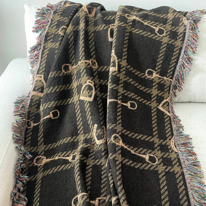 Horse bit plaid woven blanket in dark brown and gold tones, jacquard-woven 100% cotton equestrian throw with fringe edges, styled over a white sofa for classic horse-inspired home decor.