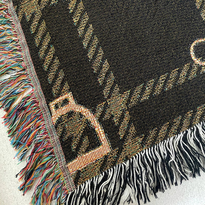 Close-up detail of horse bit plaid woven blanket in dark brown and gold, jacquard-woven 100% cotton equestrian throw with multicolored and black and white fringe edges.
