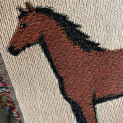 Close-up detail of jacquard-woven cotton horse motif blanket showing textured weave, rich earthy tones, and multicolored fringe edge for classic equestrian home decor.