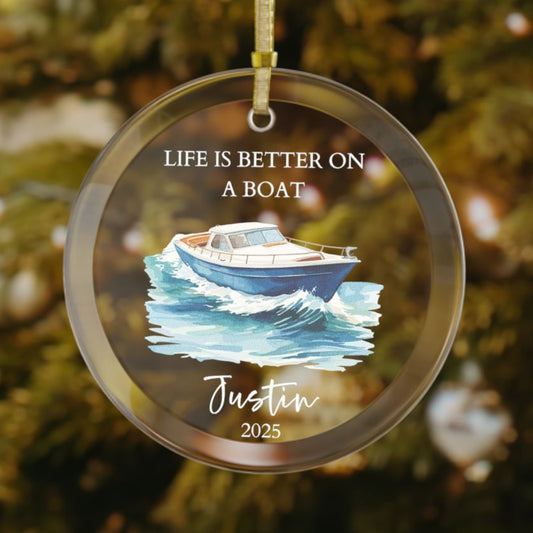 Personalized glass Christmas ornament featuring a blue cabin cruiser boat gliding through ocean waves, with the phrase "Life Is Better On A Boat," plus custom name and year.

