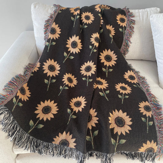 Dark brown blanket with sunflower pattern draped over a white couch.